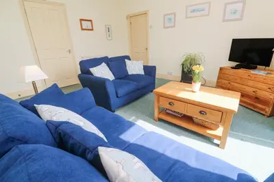 a living room with blue couches and a tv at Old Chapel Cottage in Penzance
