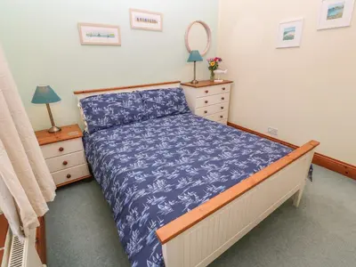 a bedroom with a bed with a blue comforter at Old Chapel Cottage in Penzance