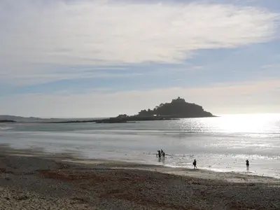 people walking on a beach with an island in the water at Old Chapel Cottage in Penzance