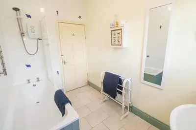 a bathroom with a tub and a sink and a mirror at Old Chapel Cottage in Penzance