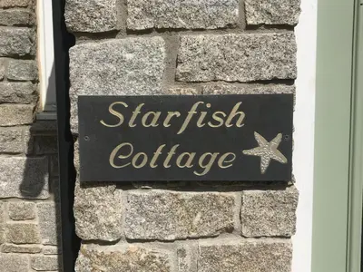 a sign for a starfish cottage on a brick wall at Starfish Cottage- private beach access- dog friendly in Charlestown
