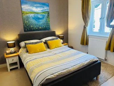 a bedroom with a bed with yellow pillows and a painting at Starfish Cottage- private beach access- dog friendly in Charlestown