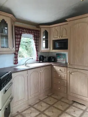 a kitchen with wooden cabinets and a sink and a window at Countryside views from a luxury mobile home near Perranporth in Perranporth