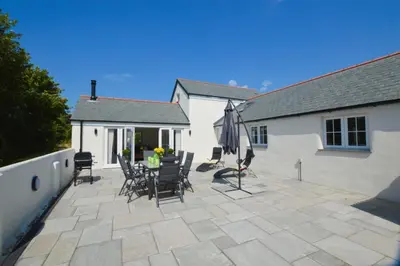 a patio with chairs and an umbrella and a building at Sunnyside Barn in Truro