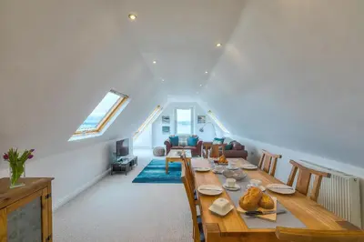 a dining room with a long table in a attic at Trevail Penthouse in St Ives