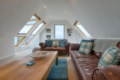 a living room with a couch and a table at Trevail Penthouse in St Ives