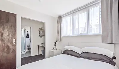 a white bedroom with a large bed and windows at Alderberry Lodge in Newquay