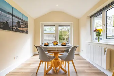 a dining room with a table and chairs and windows at Cornish Holiday - Meadow Rise in Saint Columb Major