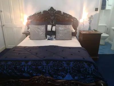 a bedroom with a large bed with a wooden headboard at Arches B&B in St Austell