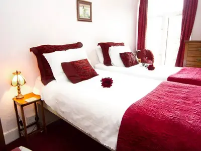 two beds in a hotel room with red and white pillows at Arches B&B in St Austell