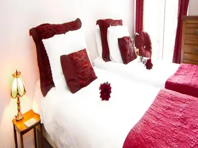 a bedroom with two beds with red and white pillows at Arches B&B in St Austell
