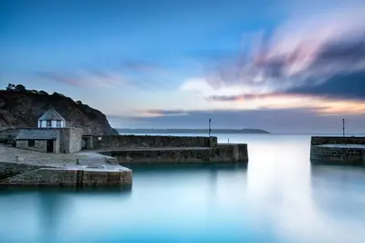 a lighthouse on a pier in the water at sunset at So Tranquil in Charlestown