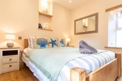 a bedroom with a bed and a mirror on the wall at Sandpiper, apartment across from the beach in Marazion