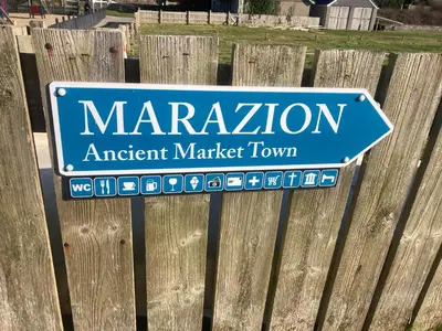 a sign for marmiteagent market town on a wooden fence at Sandpiper, apartment across from the beach in Marazion