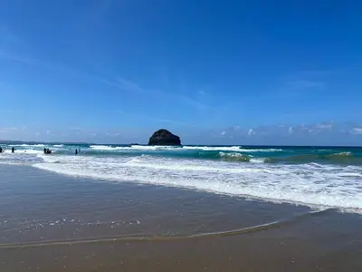 a beach with a large rock in the ocean at Buena Vista in Tintagel