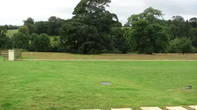 a large green field with trees in the background at Waterfall Cottage in Launceston