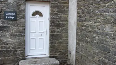 a white door on the side of a brick building at Waterfall Cottage in Launceston