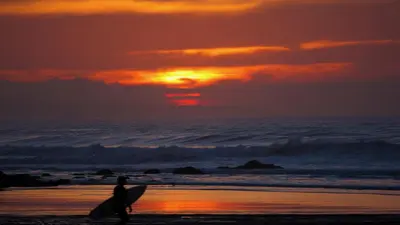 a person walking on the beach with a surfboard at THE HYDE- secret hide away, near the beach. in Truro
