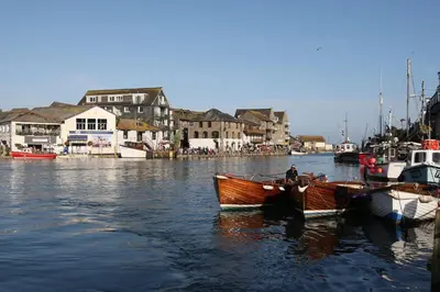 a man is sitting in a boat in the water at Polmear Harbour View With Terrace in Looe
