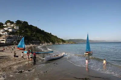a group of people on a beach with boats in the water at Polmear Harbour View With Terrace in Looe