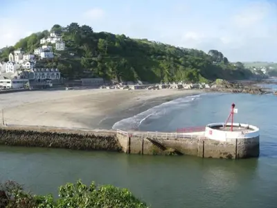 a boat in the water next to a beach at Lanescot, Harbour View With Terrace in Looe