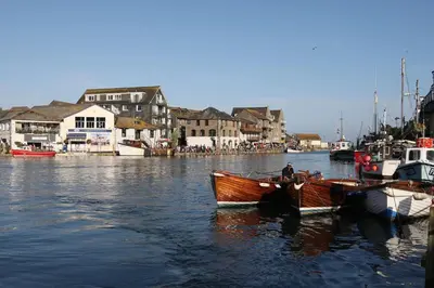 a man is sitting in a boat in the water at Lanescot, Harbour View With Terrace in Looe