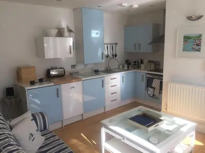 a kitchen with blue cabinets and a glass table at Lanescot, Harbour View With Terrace in Looe