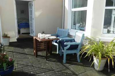a patio with two blue chairs and a table at Lanescot, Harbour View With Terrace in Looe