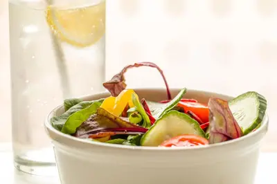 a salad in a bowl next to a glass of water at Holiday Inn Express - Bodmin - Victoria Junction by IHG in Bodmin