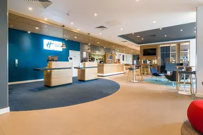 a lobby with a blue wall and tables and chairs at Holiday Inn Express - Bodmin - Victoria Junction by IHG in Bodmin