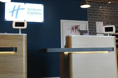 a blue wall with two tables and a sign at Holiday Inn Express - Bodmin - Victoria Junction by IHG in Bodmin