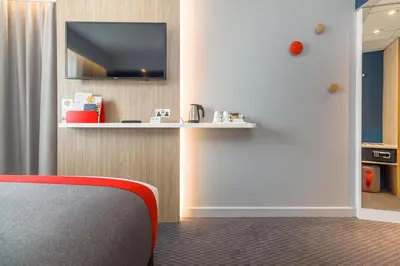 a room with a red chair and a tv on a wall at Holiday Inn Express - Bodmin - Victoria Junction by IHG in Bodmin