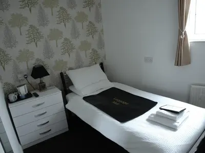 a small bedroom with a bed and a dresser at Elnor Guest House in Liskeard