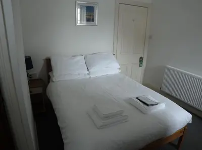 a white bed with two towels on top of it at Elnor Guest House in Liskeard