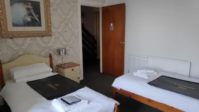 a room with two beds and a picture on the wall at Elnor Guest House in Liskeard