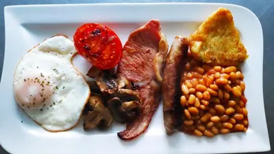 a plate of breakfast food with eggs bacon beans and toast at Elnor Guest House in Liskeard