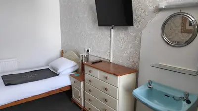a small bedroom with a bed and a mirror at Elnor Guest House in Liskeard