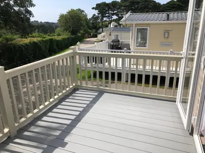 a deck with a white railing and a house at Newquay Blue Water in Newquay