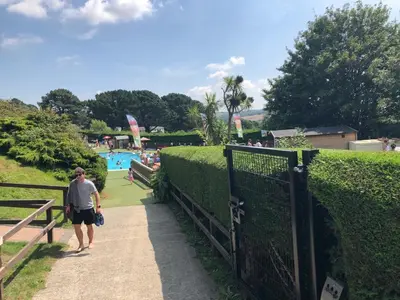 a man walking down a walkway next to a hedge at Newquay Blue Water in Newquay
