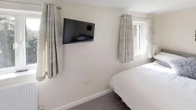 a bedroom with a bed and a tv on the wall at The Woodland Collection, 10 mins from beaches in Hayle