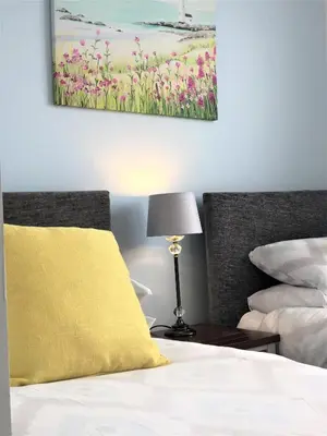 a bedroom with a bed with a yellow pillow and a lamp at Newquay Escape, 5 spacious ensuite bedrooms & parking- Simplycheckin in Newquay