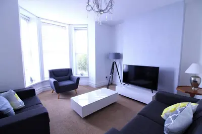a living room with a couch and a flat screen tv at Newquay Escape, 5 spacious ensuite bedrooms & parking- Simplycheckin in Newquay