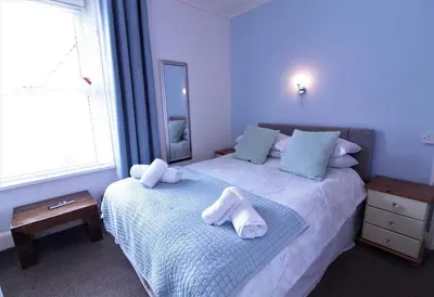 a bedroom with a bed with towels on it at Newquay Escape, 5 spacious ensuite bedrooms & parking- Simplycheckin in Newquay
