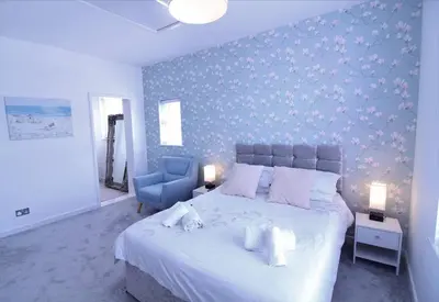 a bedroom with a large bed and a blue wall at Newquay Escape, 5 spacious ensuite bedrooms & parking- Simplycheckin in Newquay