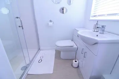 a bathroom with a shower and a sink and a toilet at Newquay Escape, 5 spacious ensuite bedrooms & parking- Simplycheckin in Newquay