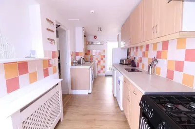 a kitchen with orange and white tiles on the wall at Newquay Escape, 5 spacious ensuite bedrooms & parking- Simplycheckin in Newquay