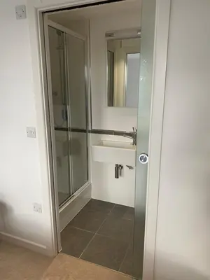 a bathroom with a sink and a glass shower at The Apartment Boscawen Woods in Truro