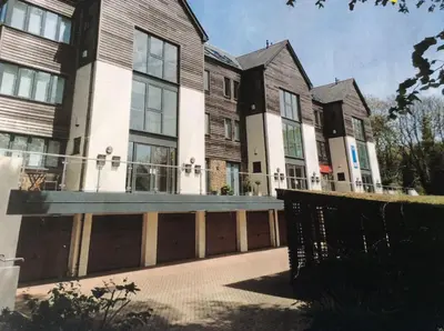a large building with a fence in front of it at The Apartment Boscawen Woods in Truro