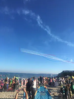 a crowd of people on a beach with a helicopter at 'the inlet' falmouth in Falmouth