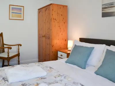 a bedroom with a bed and a wooden cabinet at Moor View in Delabole